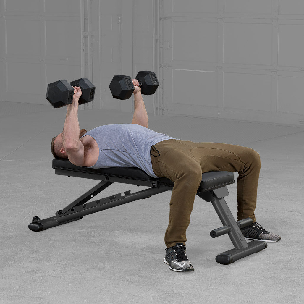 Man pressing hex dumbbells while lying on a Body-Solid GFID225B flat bench