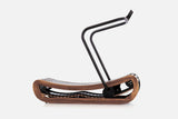 Side view of a curved manual treadmill with a medium-brown wood frame, black slats, and a raised black handlebar