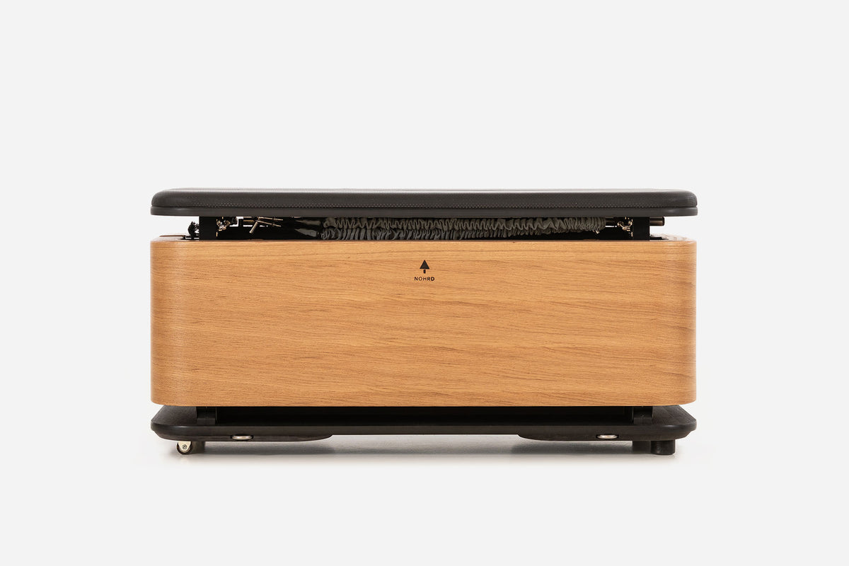 Front view of a pale oak storage bench with the padded lid raised and resistance bands visible inside